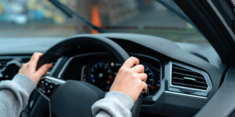 both hands gripping the steering wheel