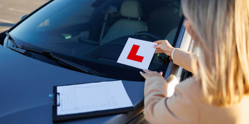 woman placing an l-plate on car windscreen