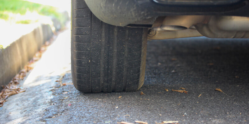 Wheel of car parked alongside kerb