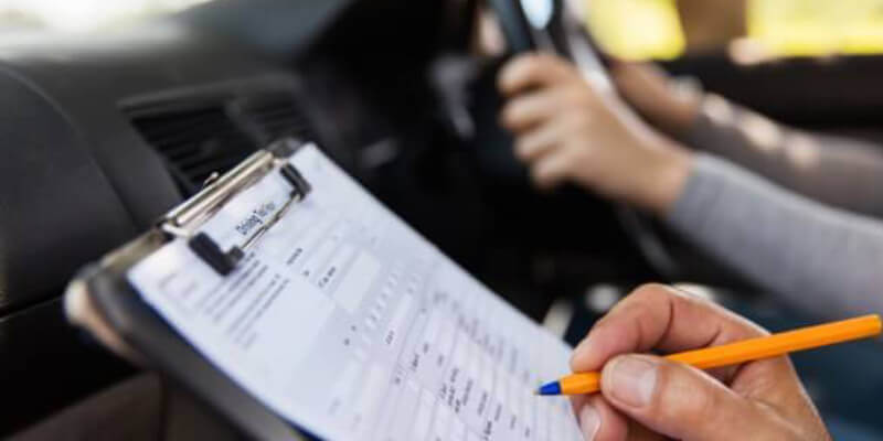 hand holding a pen marking the driving test marking sheet